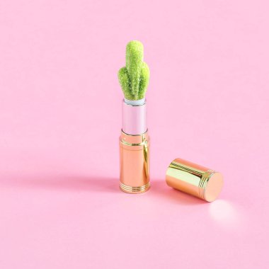 Tüp ruj ve pastel pembe bir arka plan üzerinde kaktüs şeklinde şeker. Minimalist tarzı. Renk ve şekil yaratıcı bir fikir. Tema gıda ve tatlı kötüye fanteziler