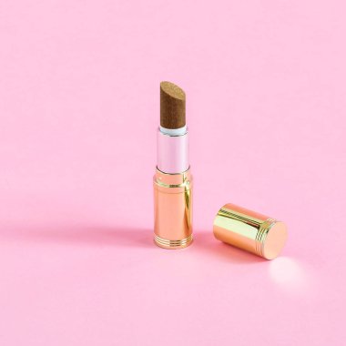 Tüp ruj ve pastel pembe bir arka plan üzerinde bademli çikolata şeker. Minimalist tarzı. Renk ve şekil yaratıcı bir fikir. Tema gıda ve tatlı kötüye fanteziler