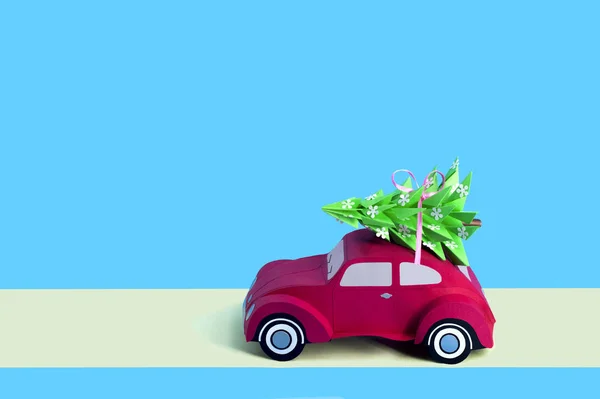 Red paper retro car carries Christmas tree