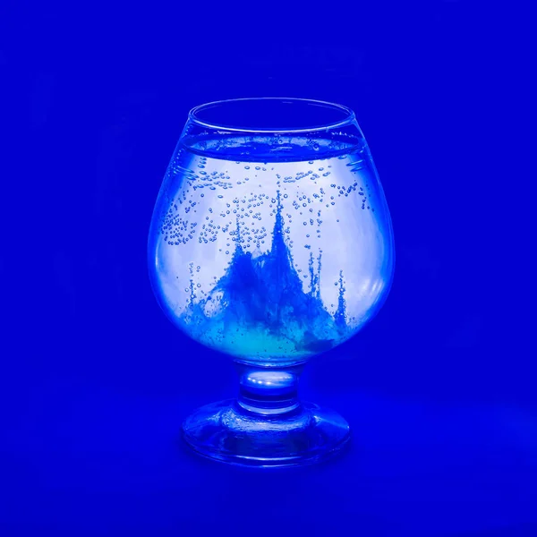 Magic vessel on blue background. Egg protein in water forms beautiful