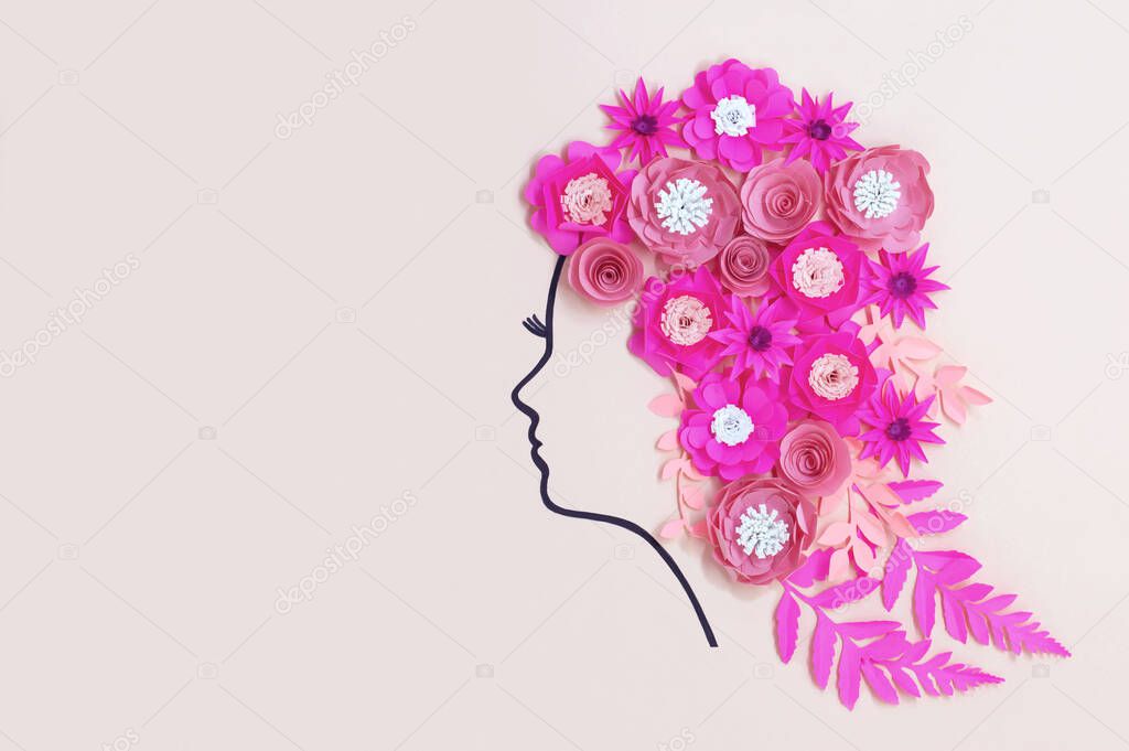 Silhouette of female head painted with felt-tip pen with paper flowers instead of hairstyle. Real volumetric handmade paper objects. Paper craft and art. Greeting card for Women's Day. Copy space