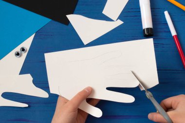 Çocuk Babalar Günü için kart hazırlıyor. Karantina sırasında çocuk gemisi. COVID-19 koronavirüs salgını sırasında çocukları nasıl cezbedeceklerini. Adım adım fotoğraflarım. Üçüncü adım. Parmaklarını kağıttan kes.