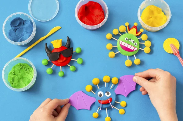 Child makes scary coronaviruses from modeling dough. Modeling from clay or dough, children\'s craft during quarantine. DIY. How to captivate children at home during coronavirus pandemic
