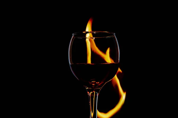 Vidrio con vino encendido y llama sobre un aislamiento de fondo negro — Foto de Stock