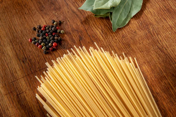 Pasta mit Lorbeerblatt und Gewürzen auf einem Holztisch, Lebensmittel aus nächster Nähe — Stockfoto