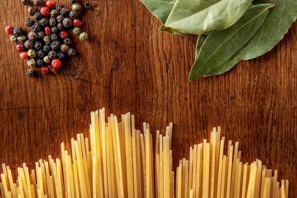 Pasta mit Lorbeerblatt und Gewürzen auf einem Holztisch, Lebensmittel aus nächster Nähe — Stockfoto