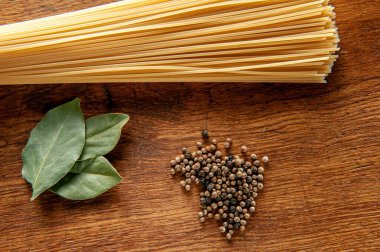 Ahşap bir masada defne yaprağı ve biberli makarna, yakın plan yiyecek.