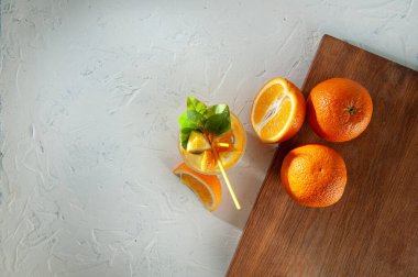 Portakal dilimli limonata ve beyaz arka planda tam portakal ve bakire tahtası. Yaz havası ve sabah kahvaltısı