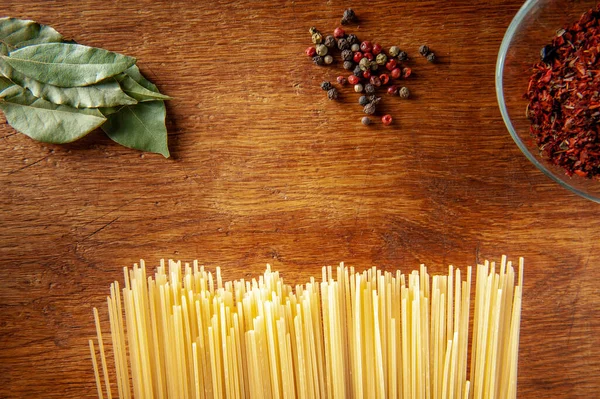 Pasta mit Lorbeerblatt und Gewürzen auf einem Holztisch, Lebensmittel aus nächster Nähe — Stockfoto