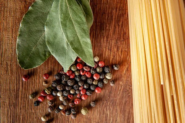 Pasta mit Lorbeerblatt und Gewürzen auf einem Holztisch, Lebensmittel aus nächster Nähe — Stockfoto