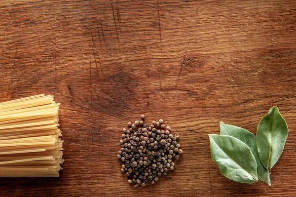 Nudeln mit Lorbeerblatt und Pfeffer auf einem Holztisch, Lebensmittel aus nächster Nähe — Stockfoto