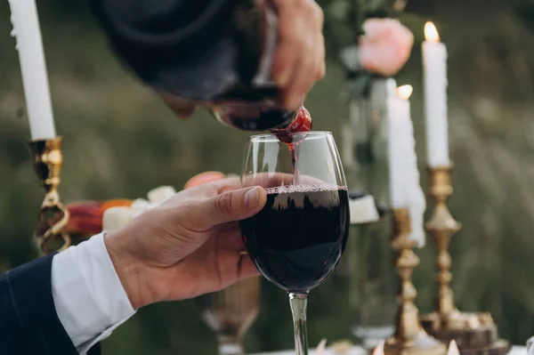 Main masculine verse du vin dans un verre lors d'un dîner romantique aux chandelles — Photo