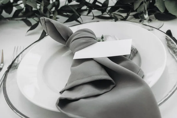 Een bord met een opschrift plaat naast een vork en mes op een wit tafelkleed. — Stockfoto
