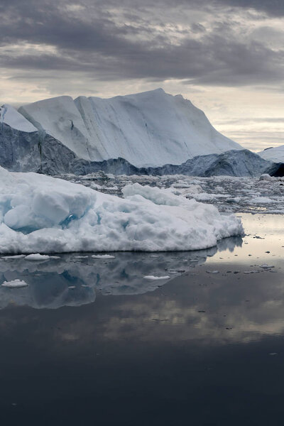 Polar regions of Earth. Icebergs of various forms and sizes. Climatic changes and growth of average annual temperature on the planet. Reduction of the area of polar ices and catastrophic thawing.