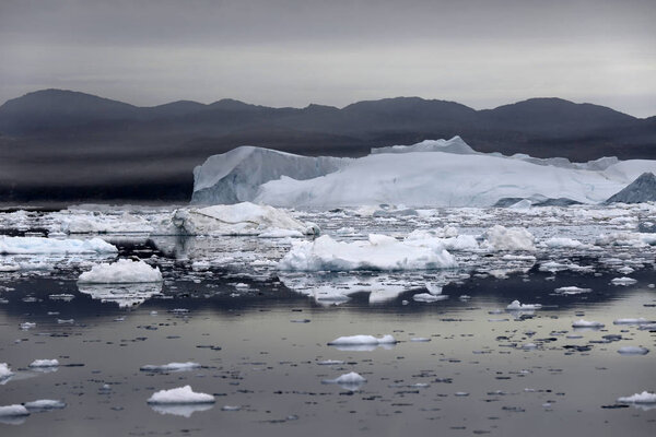 Polar regions of Earth. Icebergs of various forms and sizes. Climatic changes and growth of average annual temperature on the planet. Reduction of the area of polar ices and catastrophic thawing.