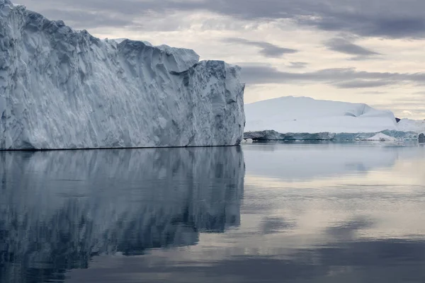 Polar regions of Earth. Icebergs of various forms and sizes. Climatic changes and growth of average annual temperature on the planet. Reduction of the area of polar ices and catastrophic thawing.