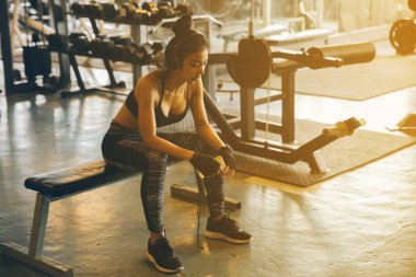 Onun egzersiz yaptıktan sonra spor salonunda spor salonu sandalyeye oturan genç kadın. Kadın