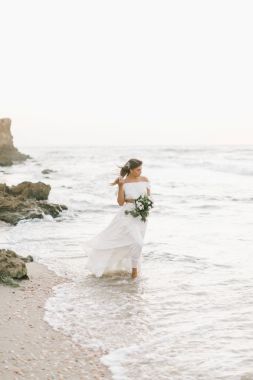 güzel kız gün batımında sahilde yürüyüş