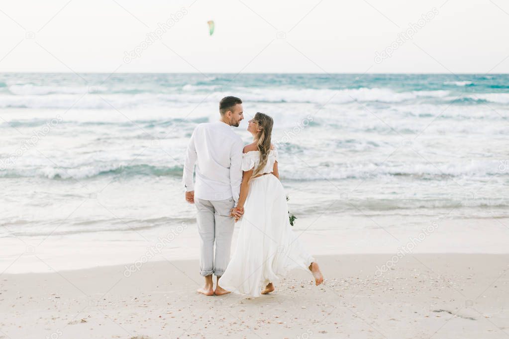Beautiful loving couple walking along the beach at sunset