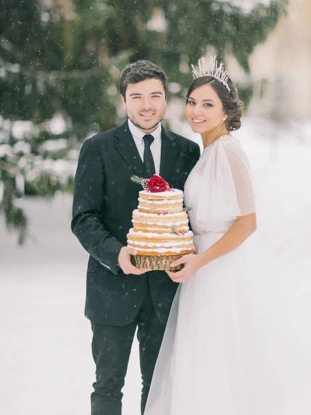 wedding in the winter, couple holding a wedding cake