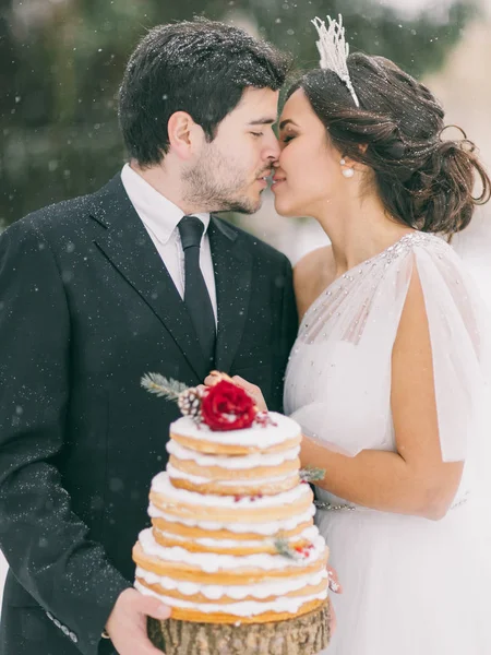 wedding in the winter, couple holding a wedding cake