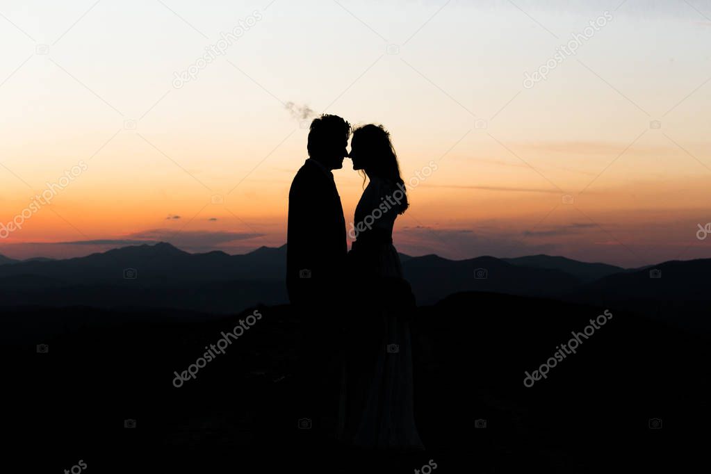silhouette of young couple standing at sunset outdoors