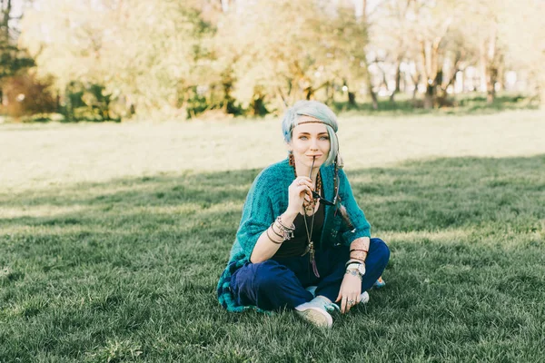 Yeşil park yeşil çimenlerin üzerinde oturan oturan genç boho kadın