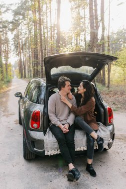 Genç ve güzel bir çift bir arabanın bagajında birlikte rahatlıyor.