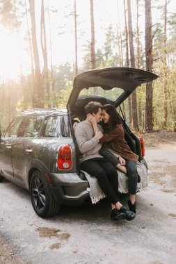 Genç ve güzel bir çift bir arabanın bagajında birlikte rahatlıyor.