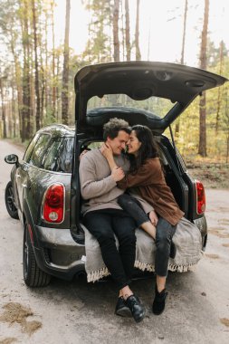 Genç ve güzel bir çift bir arabanın bagajında birlikte rahatlıyor.