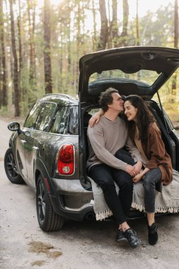 Genç ve güzel bir çift bir arabanın bagajında birlikte rahatlıyor.