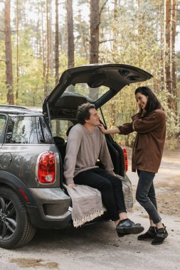 Genç ve güzel bir çift bir arabanın bagajında birlikte rahatlıyor.