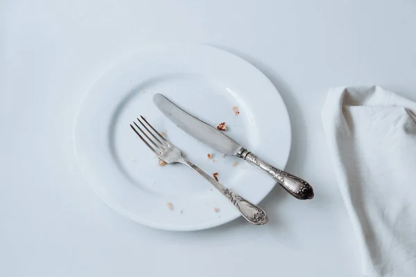 Біла тарілка з виделкою, ножем і збита на білому тлі Ліцензійні Стокові Зображення