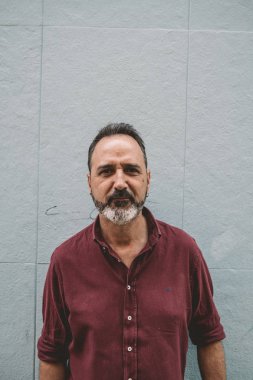 Gri duvarda gri sakallı adam