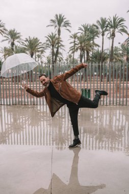 Şeffaf şemsiyeli rüzgâr tarafından sürüklenen adam