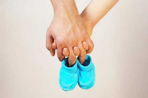 Happy young parents hold in their hands baby shoes of future chi — Stock Photo, Image