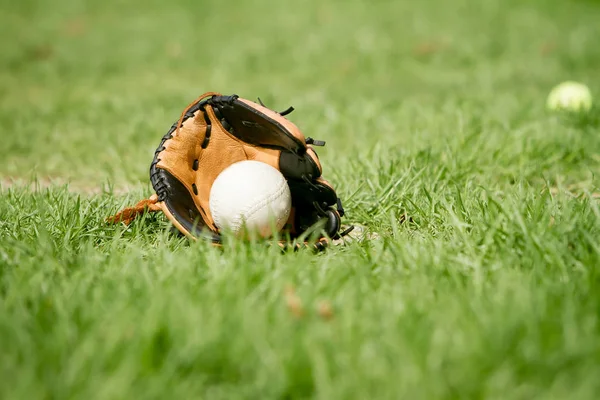 Бейсбол и перчатка лежат на поле — стоковое фото
