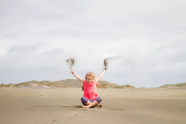 Jeune fille enfant jetant du sable — Photo