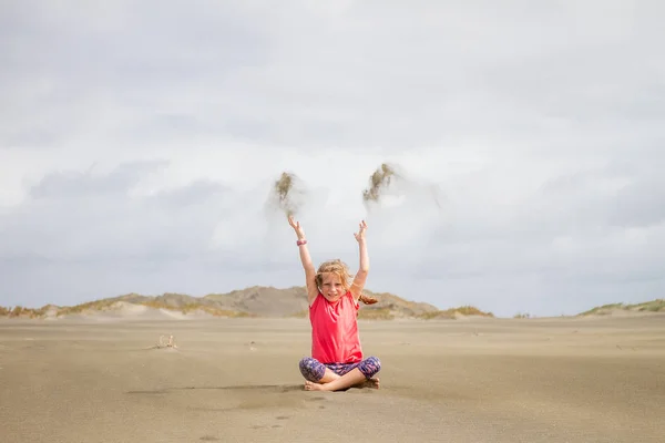 Jong kind meisje zand gooien — Stockfoto