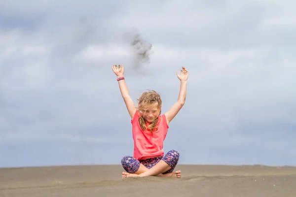 Молода дівчинка кидає пісок — стокове фото