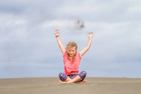 Niña joven lanzando arena — Foto de Stock