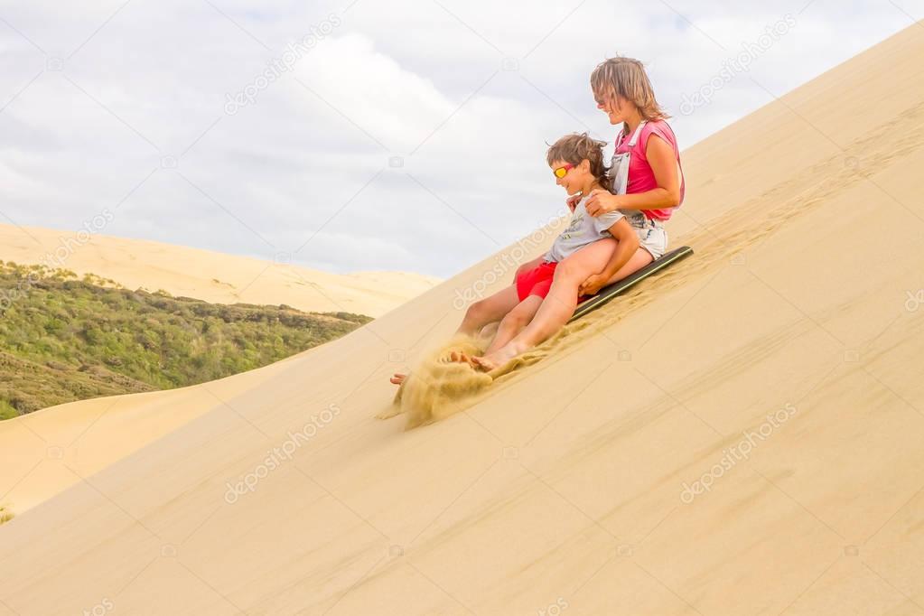 Mother and son sliding board on sand