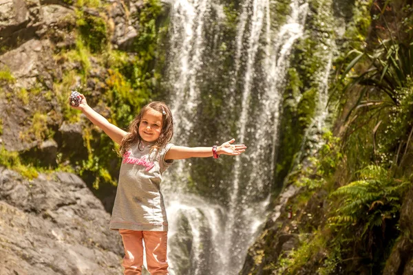 Flicka nära vackra vatten faller i skogen — Stockfoto