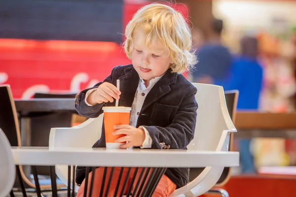 Barn pojke dricka saft i café — Stockfoto