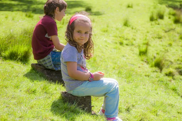 Barn flicka och pojke sitta på stenar — Stockfoto