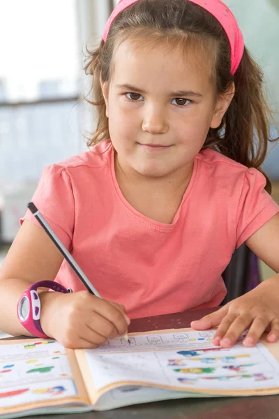 Unga barn flicka skriver i anteckningsbok — Stockfoto