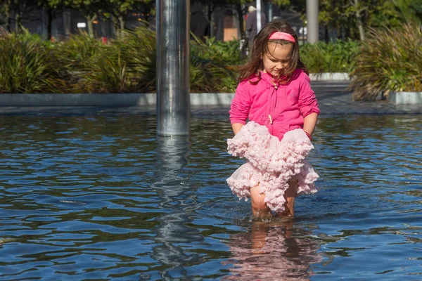 Girl holds skirt in pool