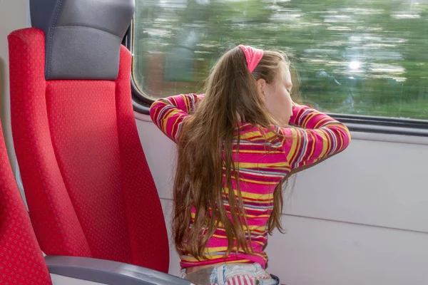 Молодая маленькая кавказская девочка, путешествующая на поезде — стоковое фото