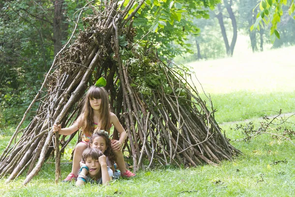 Bambini che giocano accanto alla casa bastone di legno — Foto Stock