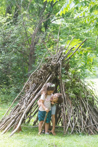 Kinderen spelen naast houten stok huis — Stockfoto